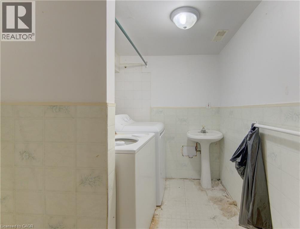 Shared laundry space featuring a pedestal sink, a ceiling-mount light fixture, and tiled flooring - 48 Breithaupt Street, Kitchener, ON - Indoor Photo Showing Laundry Room