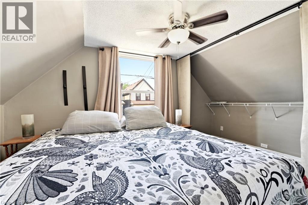 Attic bedroom featuring an angled ceiling and a window with exterior residential surroundings - 23 Britannia Avenue, Hamilton, ON - Indoor Photo Showing Bedroom