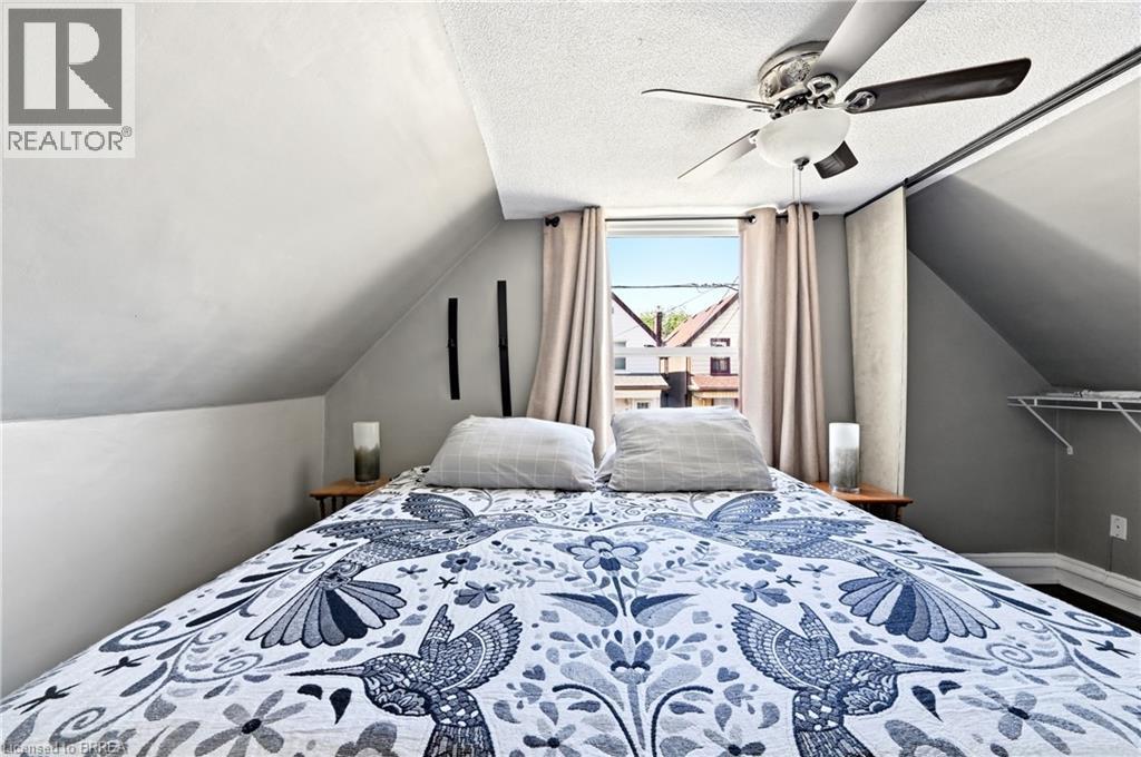 Attic space featuring a window, built-in shelving, vaulted ceilings, and a ceiling fan - 23 Britannia Avenue, Hamilton, ON - Indoor Photo Showing Bedroom