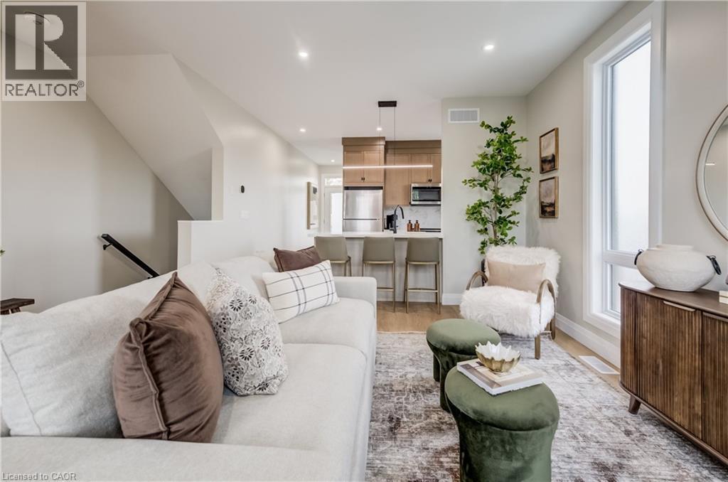 Open-concept living space featuring wood-finish flooring, recessed lighting, a modern kitchen with a breakfast bar, stainless steel appliances, and a full-height window - 210 Heritage Drive Unit# Main, Kitchener, ON - Indoor Photo Showing Living Room