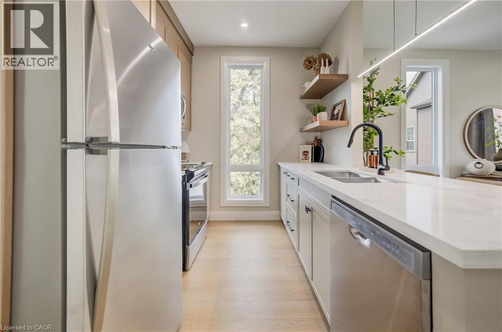 Modern kitchen featuring stainless steel appliances, light wood-finish flooring, white countertops, and a black gooseneck faucet - 210 Heritage Drive Unit# Main, Kitchener, ON - Indoor Photo Showing Kitchen With Double Sink