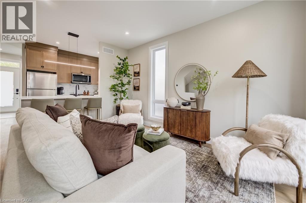 Open-concept living space with a contemporary kitchen featuring stainless steel appliances, light wood-finish cabinetry, and a central island with seating - 210 Heritage Drive Unit# Main, Kitchener, ON - Indoor Photo Showing Living Room