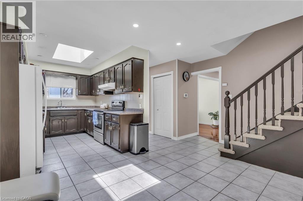 Kitchen featuring stainless steel electric range, freestanding refrigerator, a skylight, light countertops, and light tile patterned floors - 146 Bechtel Drive, Kitchener, ON - Indoor Photo Showing Kitchen