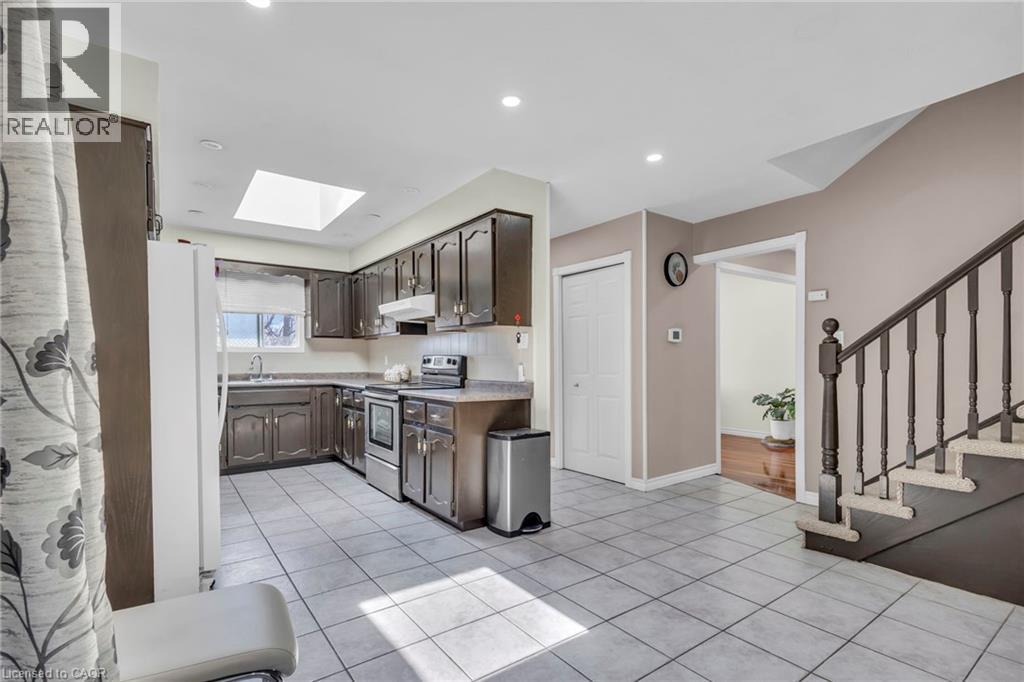 Kitchen featuring electric stove, freestanding refrigerator, light countertops, dark wood finish cabinets, and light tile patterned floors - 146 Bechtel Drive, Kitchener, ON - Indoor Photo Showing Kitchen