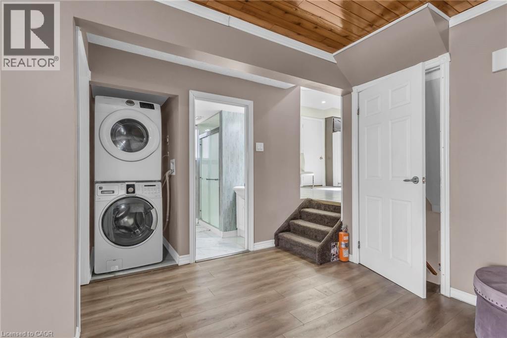 Laundry area with wood finished floors, stacked washer and dryer, crown molding, and wooden ceiling - 146 Bechtel Drive, Kitchener, ON - Indoor Photo Showing Laundry Room