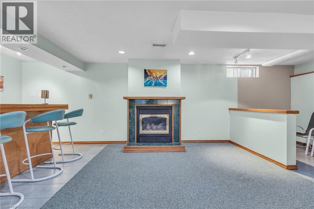 Living area with a bar, a tiled fireplace, light carpet, rail lighting, and light tile patterned flooring - 146 Bechtel Drive, Kitchener, ON - Indoor With Fireplace