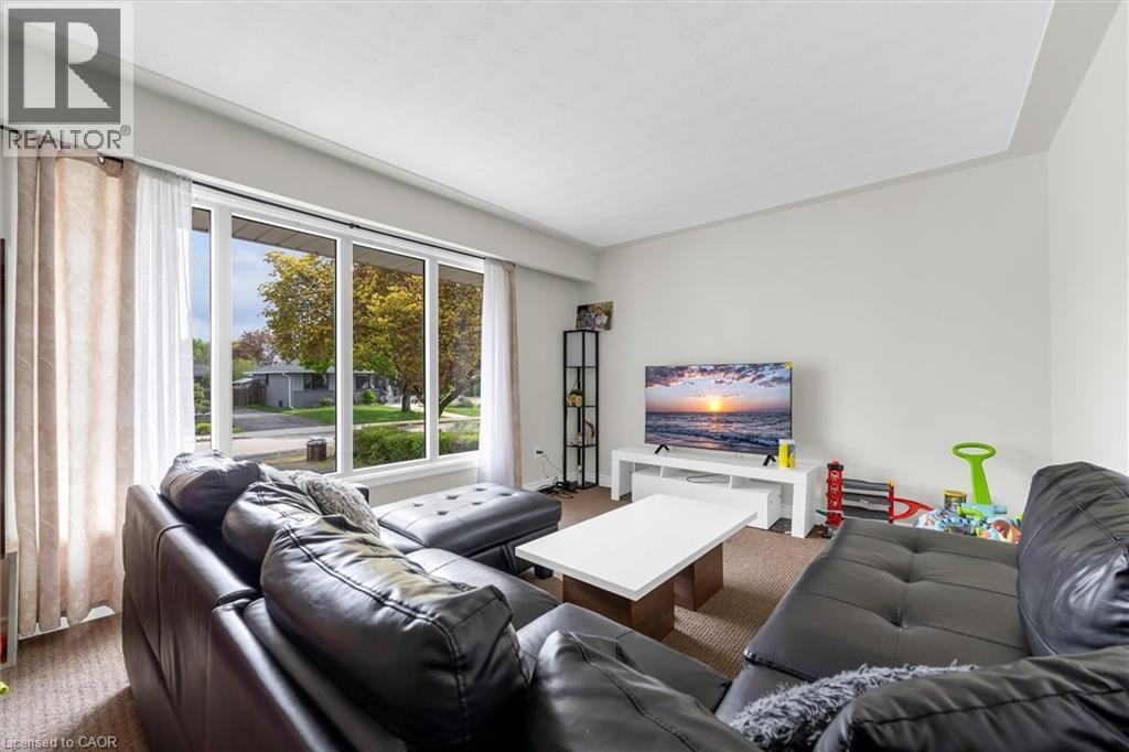 Bright living area featuring a large picture window, neutral wall paint, and textured carpet flooring - 46 Beaconsfield Drive, Hamilton, ON - Indoor Photo Showing Living Room