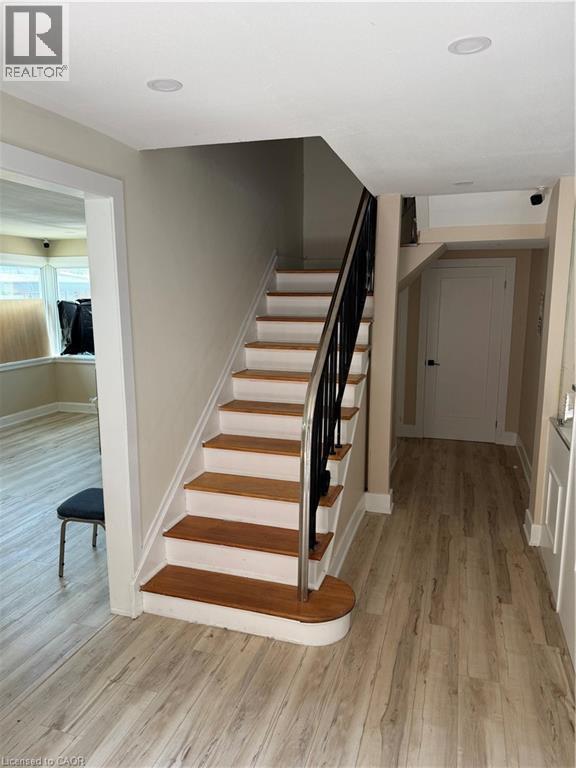 Staircase featuring wood-finish treads and risers, a wrought iron banister, and a curved bottom step - 357 Main Street E Unit# Main Floor, Hamilton, ON