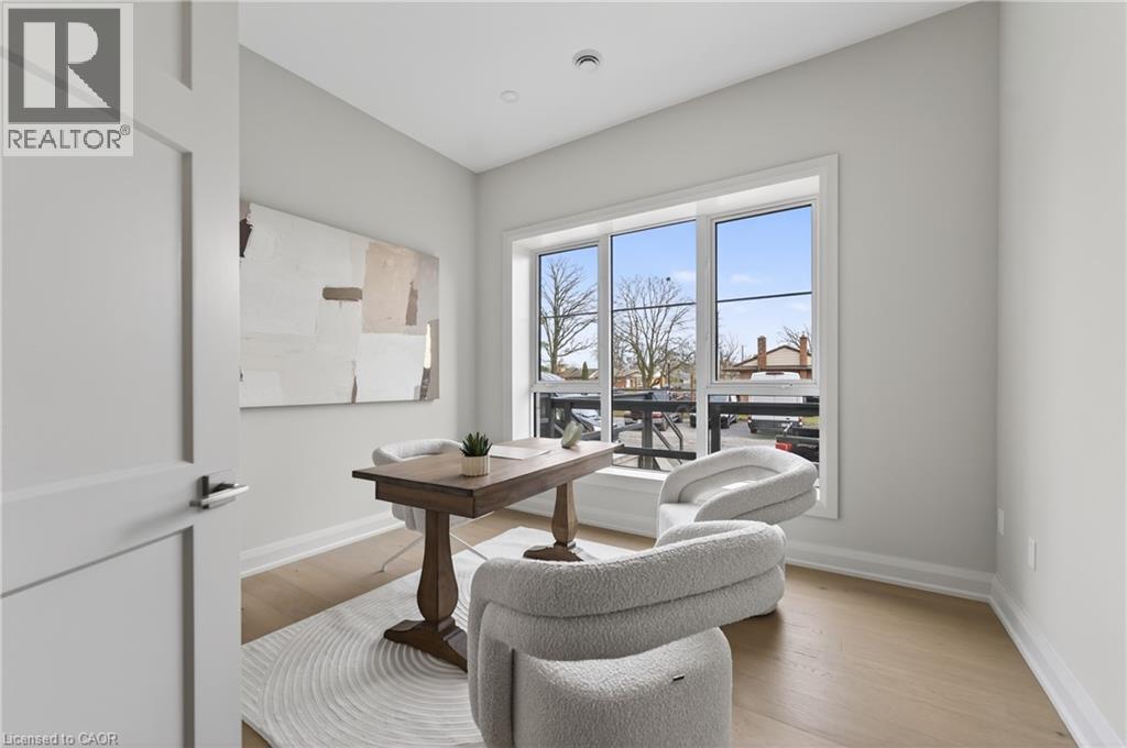 Well-lit room featuring a large window, light wood-finish flooring, recessed lighting, and a modern interior door - 2 Arbourvale Common Unit# 209, St. Catharines, ON - Indoor