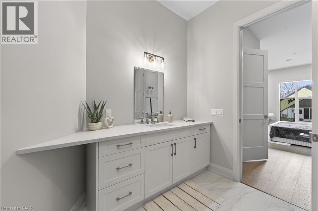 Spacious vanity with light gray cabinetry, a white countertop, and a rectangular undermount sink - 2 Arbourvale Common Unit# 209, St. Catharines, ON - Indoor Photo Showing Bathroom