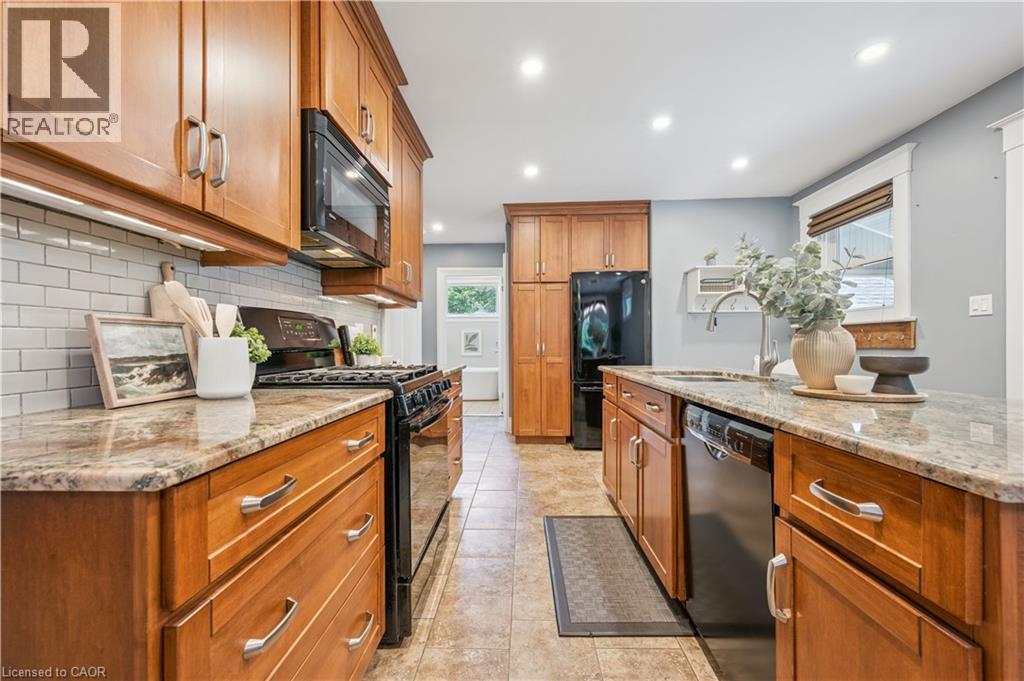 Kitchen featuring wood cabinetry, light-toned granite countertops, a subway tile backsplash, stainless steel appliances, and recessed lighting - 310 Kitchener Road, Cambridge, ON - Indoor Photo Showing Kitchen