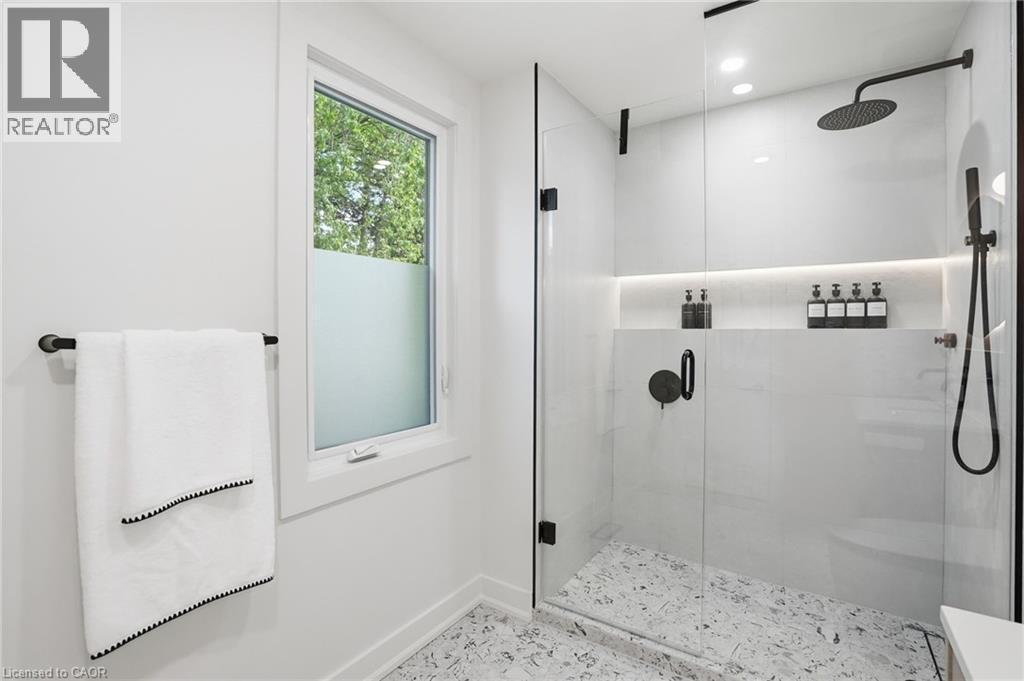 Modern shower enclosure featuring clear glass panels and matte black hardware - 345 Rankin Drive, Burlington, ON - Indoor