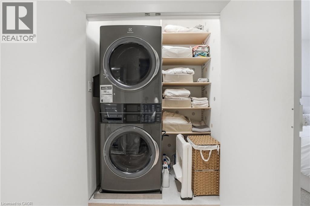 Dedicated laundry closet featuring a stacked washer and dryer unit, multiple adjustable shelving units, and a built-in utility hook - 345 Rankin Drive, Burlington, ON - Indoor Photo Showing Laundry Room
