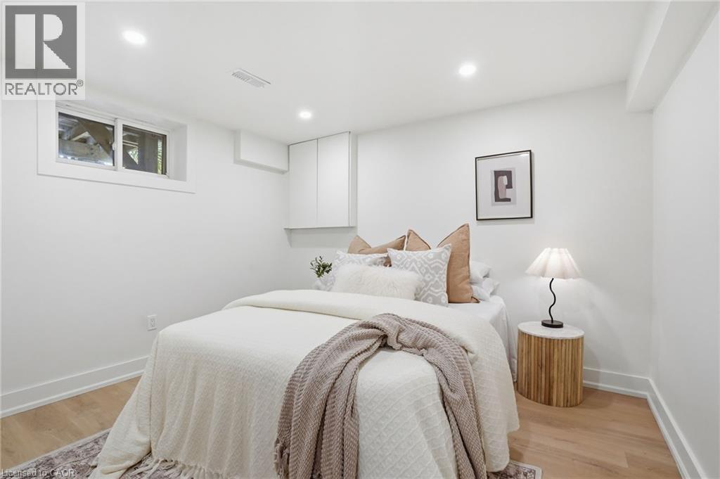 Recessed lighting illuminates this room, featuring light wood-finish flooring, white baseboards, and a window with white trim - 345 Rankin Drive, Burlington, ON - Indoor Photo Showing Bedroom