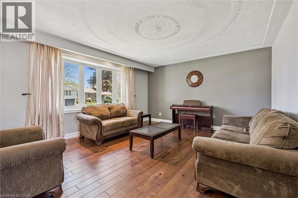 Living area featuring a detailed ceiling medallion, a large bay window, and wood-finish flooring - 47 Oakhurst Crescent, Kitchener, ON - Indoor Photo Showing Living Room
