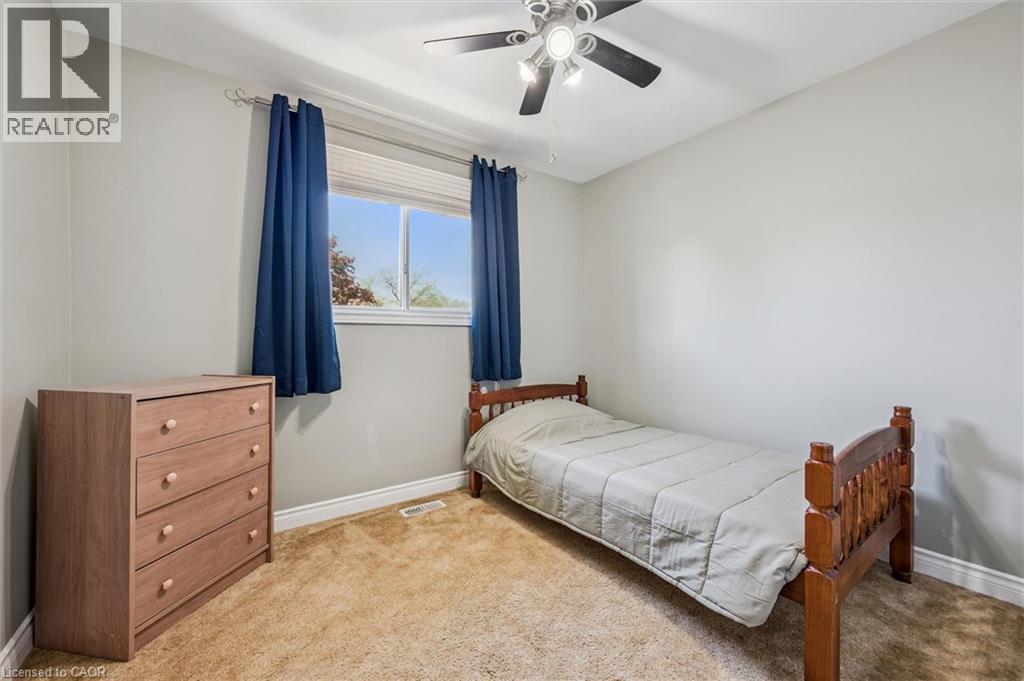 Carpeted room featuring a ceiling fan with integrated lighting, a window with blinds, and white baseboards - 47 Oakhurst Crescent, Kitchener, ON - Indoor Photo Showing Bedroom