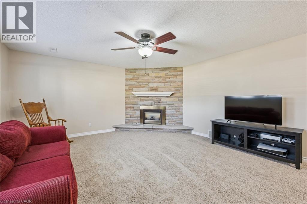 Living area featuring a corner fireplace with a stone surround, a white mantel, and a stone hearth - 47 Oakhurst Crescent, Kitchener, ON - Indoor Photo Showing Living Room With Fireplace