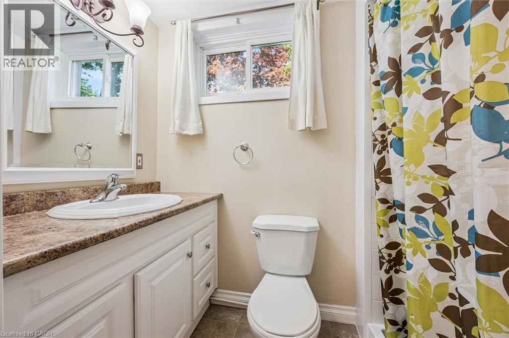 Bathroom featuring a white vanity with a brown speckled countertop, an oval undermount sink, a white framed mirror, and a toilet - 47 Oakhurst Crescent, Kitchener, ON - Indoor Photo Showing Bathroom