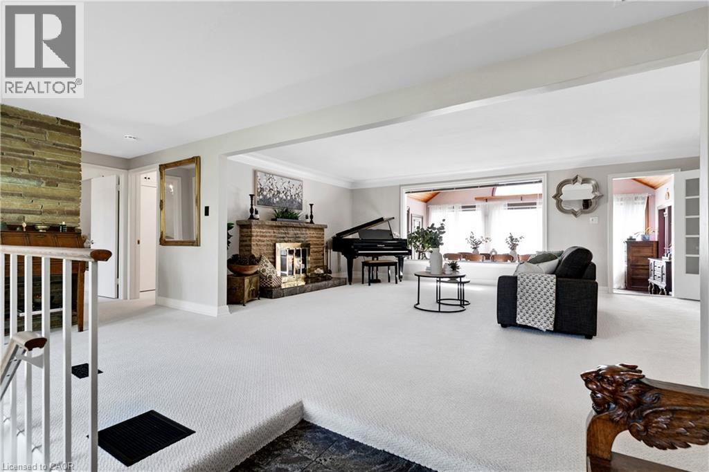 Spacious living area featuring light-colored carpeting, a brick fireplace with a detailed screen, and an expansive window line - 91 Limerick Drive, Kitchener, ON - Indoor