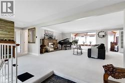 Spacious living area featuring light-colored carpeting, a brick fireplace with a detailed screen, and an expansive window line -