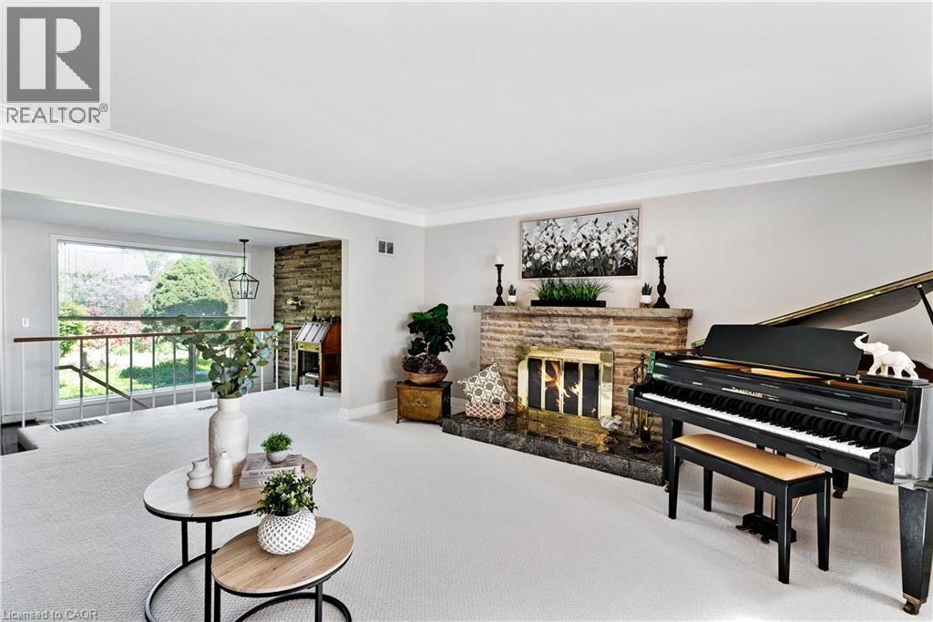 Spacious living area featuring a prominent brick fireplace with a dark stone hearth - 91 Limerick Drive, Kitchener, ON - Indoor Photo Showing Other Room With Fireplace