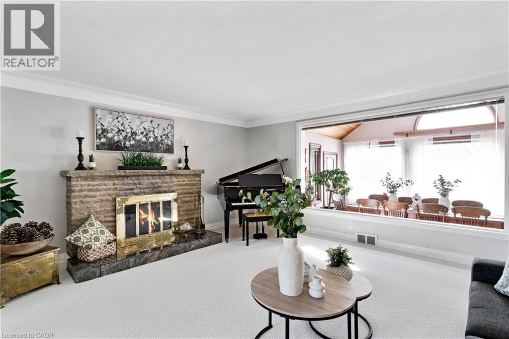 Living area featuring a stone-clad fireplace with a brass firebox, crown molding, and light-toned wall paint - 91 Limerick Drive, Kitchener, ON - Indoor Photo Showing Living Room With Fireplace