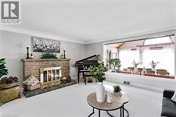 Living area featuring a stone-clad fireplace with a brass firebox, crown molding, and light-toned wall paint -