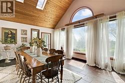 Dining space featuring a vaulted wood-paneled ceiling with skylights, an arched transom window, and a wall of floor-to-ceiling windows -