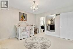 Carpeted room with a crystal chandelier, white walls, and an open doorway leading to an attached bathroom -