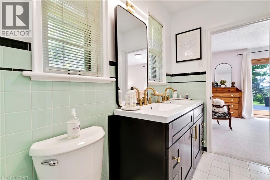 Bathroom featuring a dual-sink vanity with gold-finish fixtures, a white countertop, and dark wood cabinetry - 91 Limerick Drive, Kitchener, ON - Indoor Photo Showing Bathroom