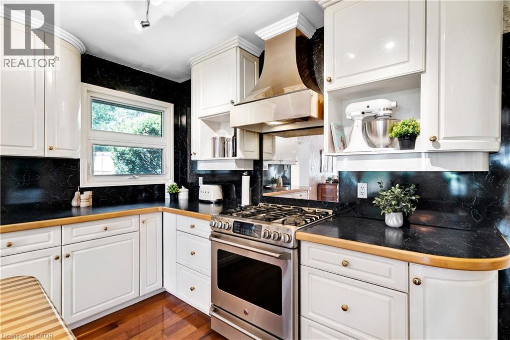 Kitchen featuring white cabinetry, dark stone countertops, and wood-finish flooring - 91 Limerick Drive, Kitchener, ON - Indoor Photo Showing Kitchen