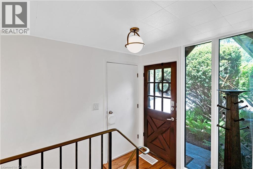 Rustic wood-paneled entry door with glass panes and a metal handle - 91 Limerick Drive, Kitchener, ON - Indoor Photo Showing Other Room