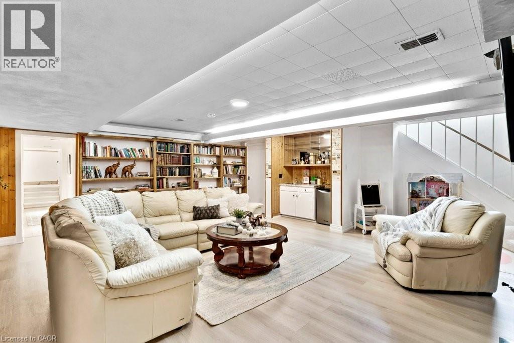 Spacious recreation room featuring recessed lighting, extensive built-in shelving, wood-finish flooring, and a wet bar with integrated cabinetry and a beverage cooler - 91 Limerick Drive, Kitchener, ON - Indoor Photo Showing Living Room