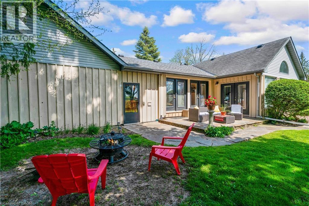 Expansive backyard featuring a stone patio, multiple exterior doors, and a fire pit area - 91 Limerick Drive, Kitchener, ON - Outdoor With Deck Patio Veranda