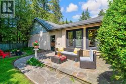 Flagstone patio with a raised section, featuring multiple large windows with dark trim, a side entry door, and a wood-paneled exterior -