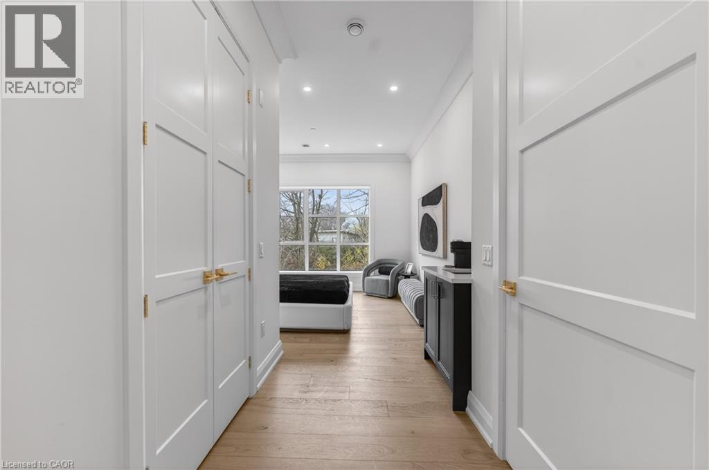 Hallway featuring light wood-finish flooring, recessed lighting, and white paneled doors with brass hardware - 2 Arbourvale Common Unit# 410, St. Catharines, ON - Indoor Photo Showing Other Room