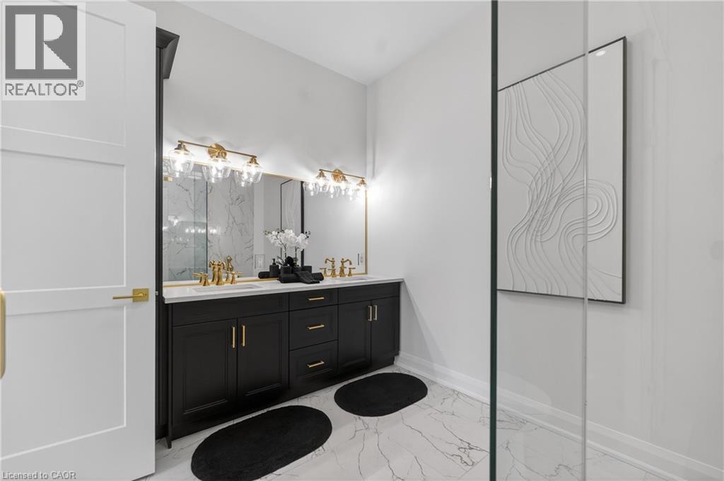 Bathroom featuring a dual vanity with black cabinetry, brass hardware, and a white countertop - 2 Arbourvale Common Unit# 410, St. Catharines, ON - Indoor Photo Showing Bathroom