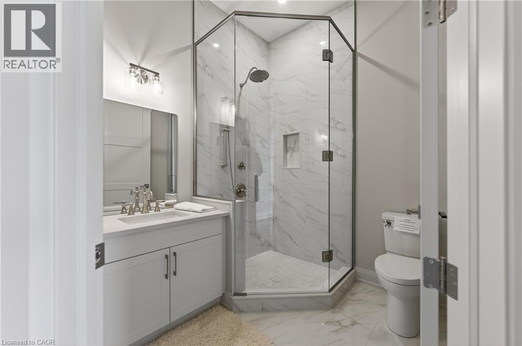 Modern bathroom featuring a glass-enclosed corner shower with full-height tile surround and an integrated niche - 2 Arbourvale Common Unit# 410, St. Catharines, ON - Indoor Photo Showing Bathroom