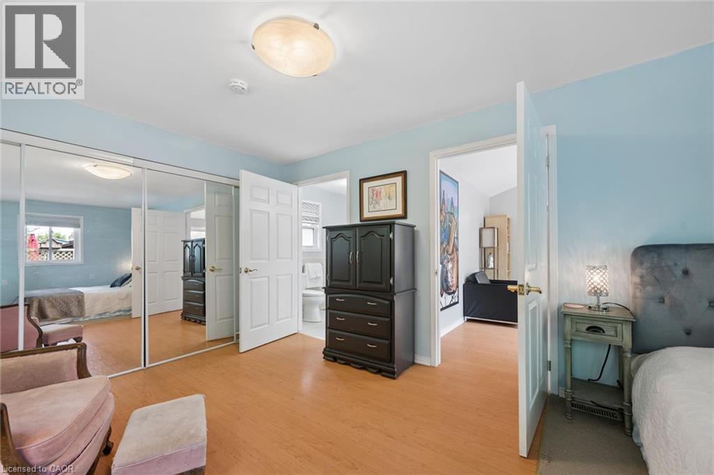 Bedroom featuring wood-finish flooring, mirrored closet doors, and an overhead flush-mount light fixture - 50 Lewis Crescent, Kitchener, ON - Indoor Photo Showing Bedroom