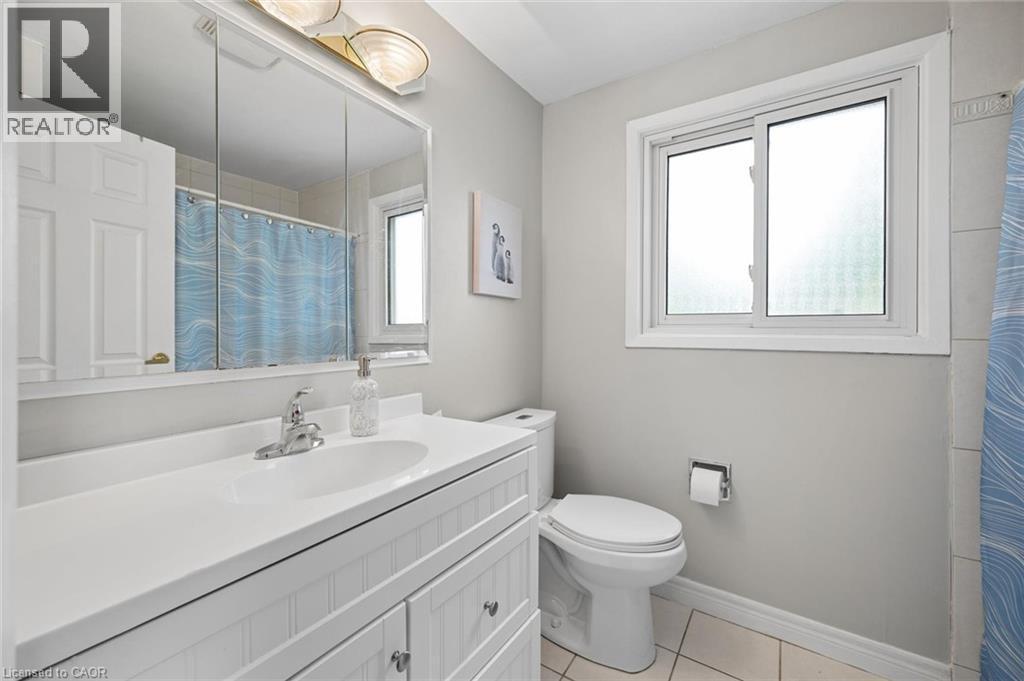 Bathroom featuring a white vanity with beadboard detailing, an integrated white sink, a chrome faucet, and a three-door mirrored medicine cabinet - 50 Lewis Crescent, Kitchener, ON - Indoor Photo Showing Bathroom