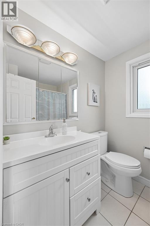 Bathroom featuring a white vanity with beadboard paneling, an integrated sink and countertop, a chrome faucet, and a large wall-mounted mirror - 50 Lewis Crescent, Kitchener, ON - Indoor Photo Showing Bathroom