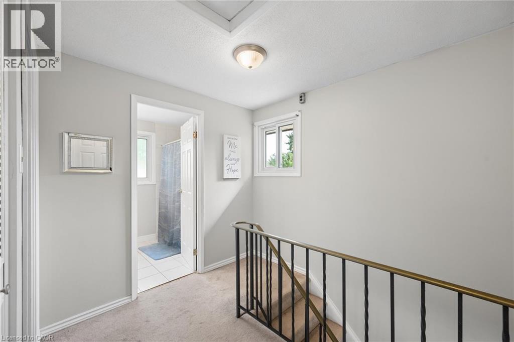 Upper landing featuring light-toned carpeting, a window with white trim, and a metal staircase railing - 50 Lewis Crescent, Kitchener, ON - Indoor Photo Showing Other Room