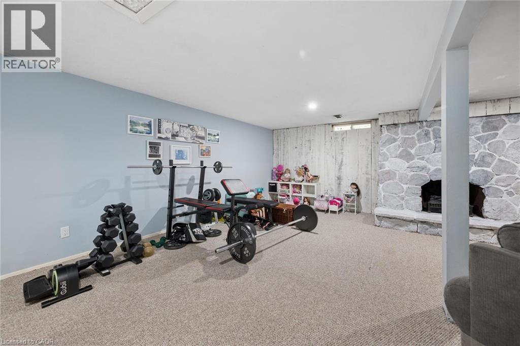 Spacious finished basement featuring recessed lighting, light blue wall paint, a stone-clad fireplace, and neutral carpet flooring - 50 Lewis Crescent, Kitchener, ON - Indoor Photo Showing Gym Room