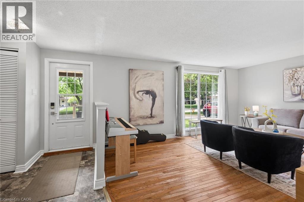 Hardwood flooring extends throughout this interior space, featuring a white paneled door with glass inserts and a large window with white framing - 50 Lewis Crescent, Kitchener, ON - Indoor
