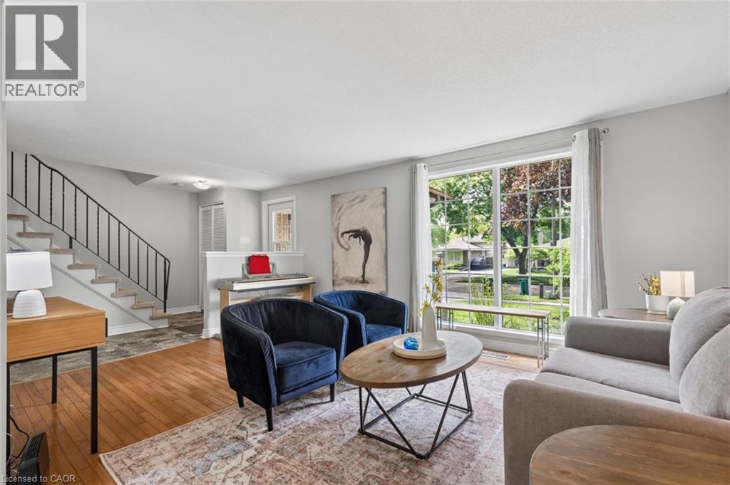 Bright living area featuring wood-finish flooring, a contemporary staircase with iron railings, a large picture window, and light gray wall paint - 50 Lewis Crescent, Kitchener, ON - Indoor Photo Showing Living Room