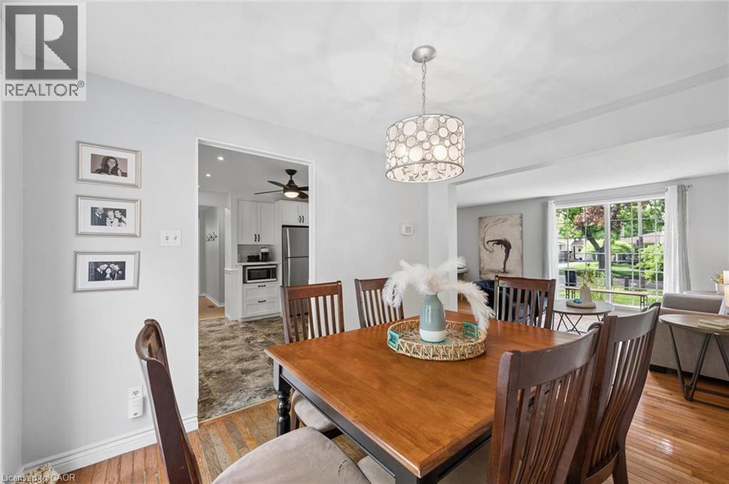 Dining area featuring wood-finish flooring, a contemporary chandelier, and an open doorway to the kitchen - 50 Lewis Crescent, Kitchener, ON - Indoor Photo Showing Dining Room