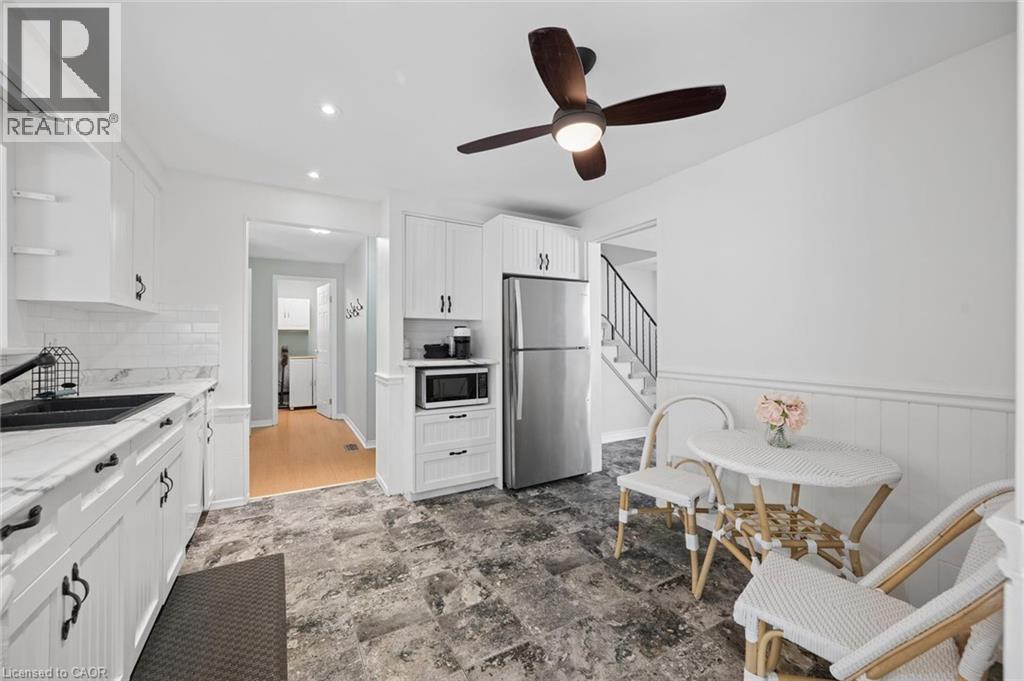 Bright kitchen featuring white cabinetry, a black sink, stainless steel appliances, and a modern ceiling fan with light - 50 Lewis Crescent, Kitchener, ON - Indoor Photo Showing Kitchen With Upgraded Kitchen