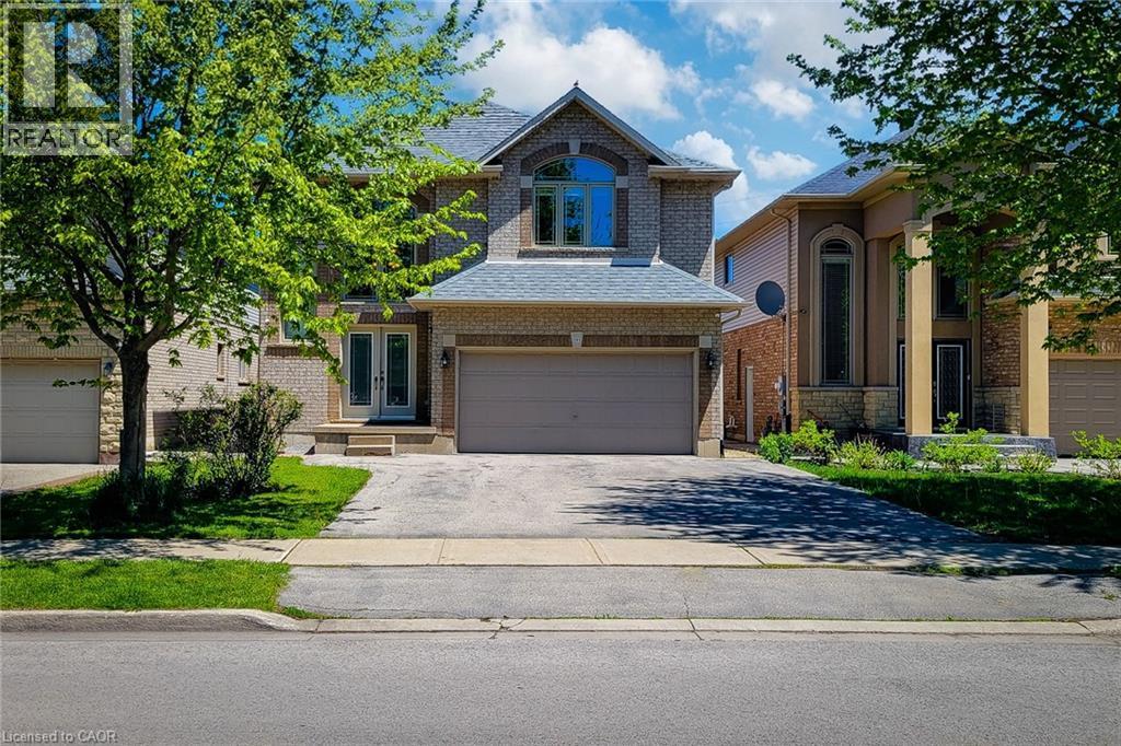 Brick exterior with a stone accent facade, featuring a prominent arched window and a double garage - 197 Cloverleaf Drive, Ancaster, ON - Outdoor With Facade