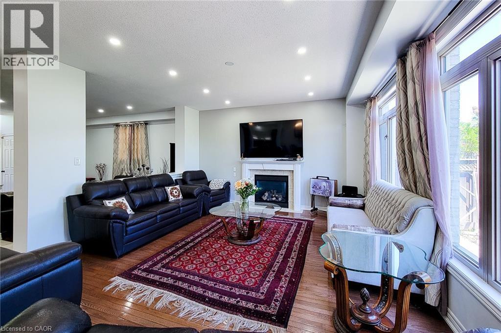 Spacious living area featuring wood-finish flooring, recessed ceiling lighting, and a white mantel fireplace - 197 Cloverleaf Drive, Ancaster, ON - Indoor Photo Showing Living Room With Fireplace