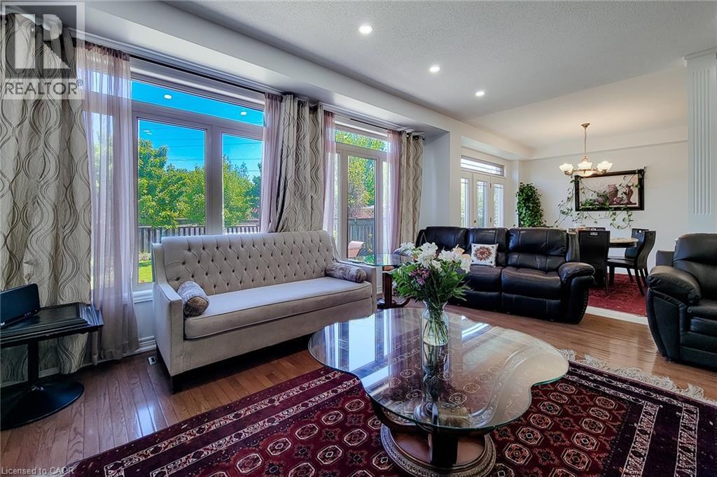 Spacious living area featuring large windows, wood-finish flooring, recessed lighting, and a chandelier in the dining area - 197 Cloverleaf Drive, Ancaster, ON - Indoor Photo Showing Living Room